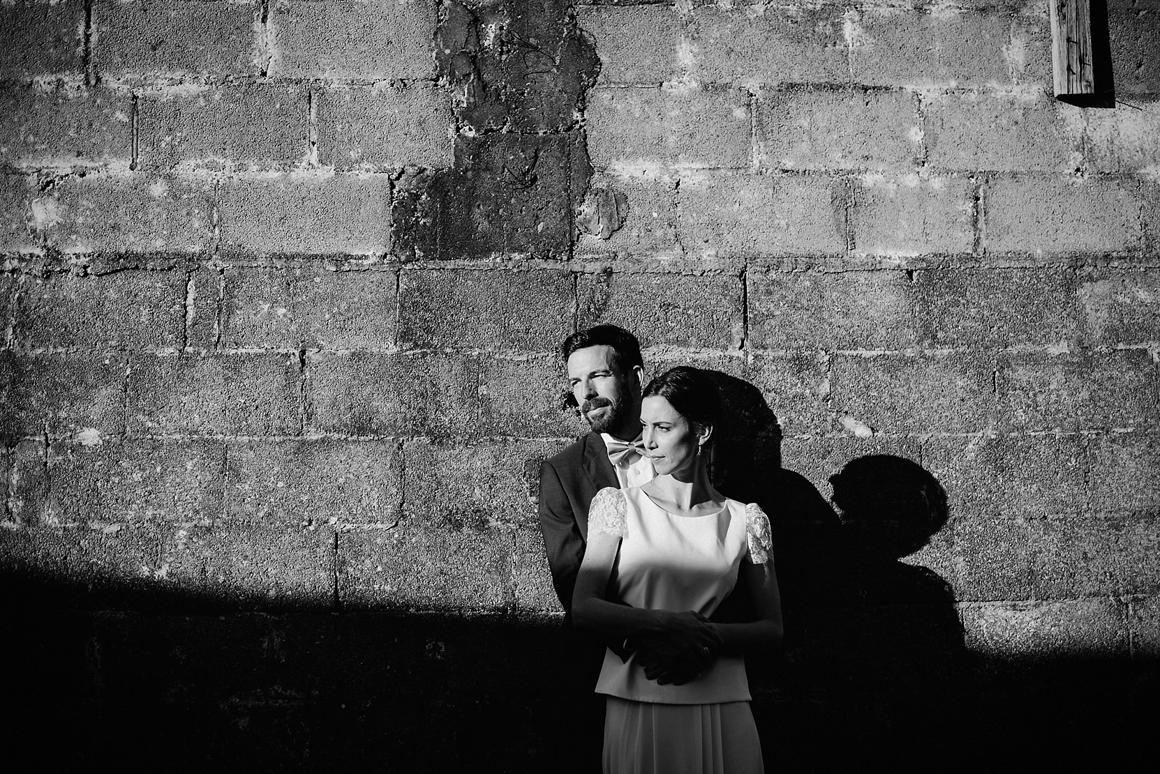 Bride and groom standing at a wall at a wedding in good light