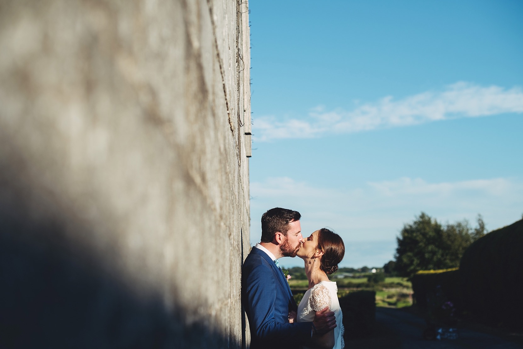 Bride and groom standing at a wall at a wedding in good light with the sky in the background