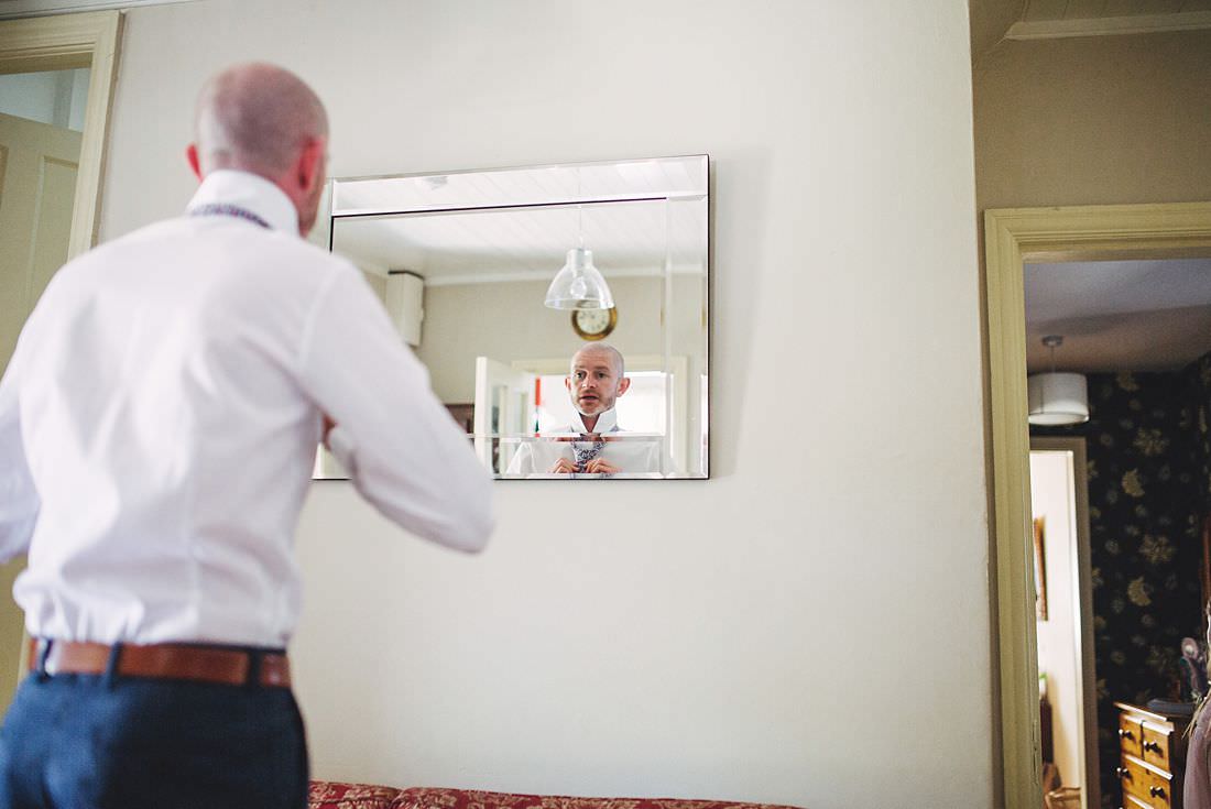 Groom looking in the mirror on the wedding morning